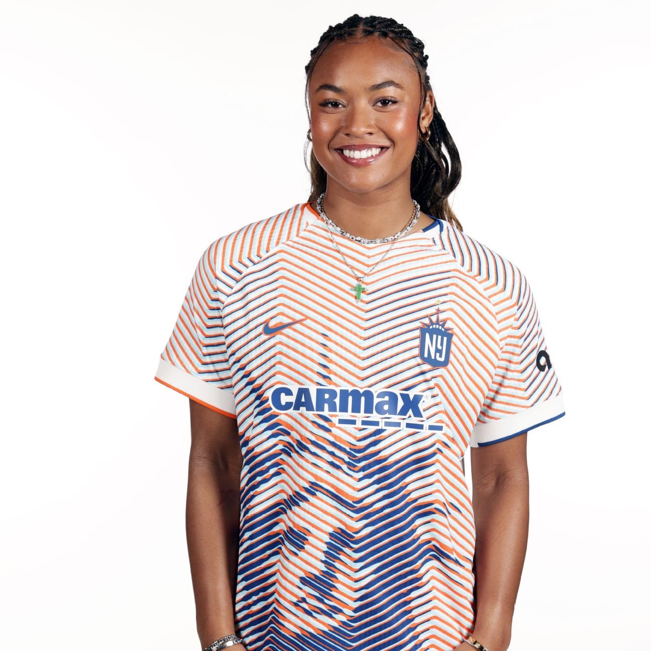 A young black and asian woman wearing a soccer jersey with red and blue patterned stripes and the Statue of Liberty on a white background.