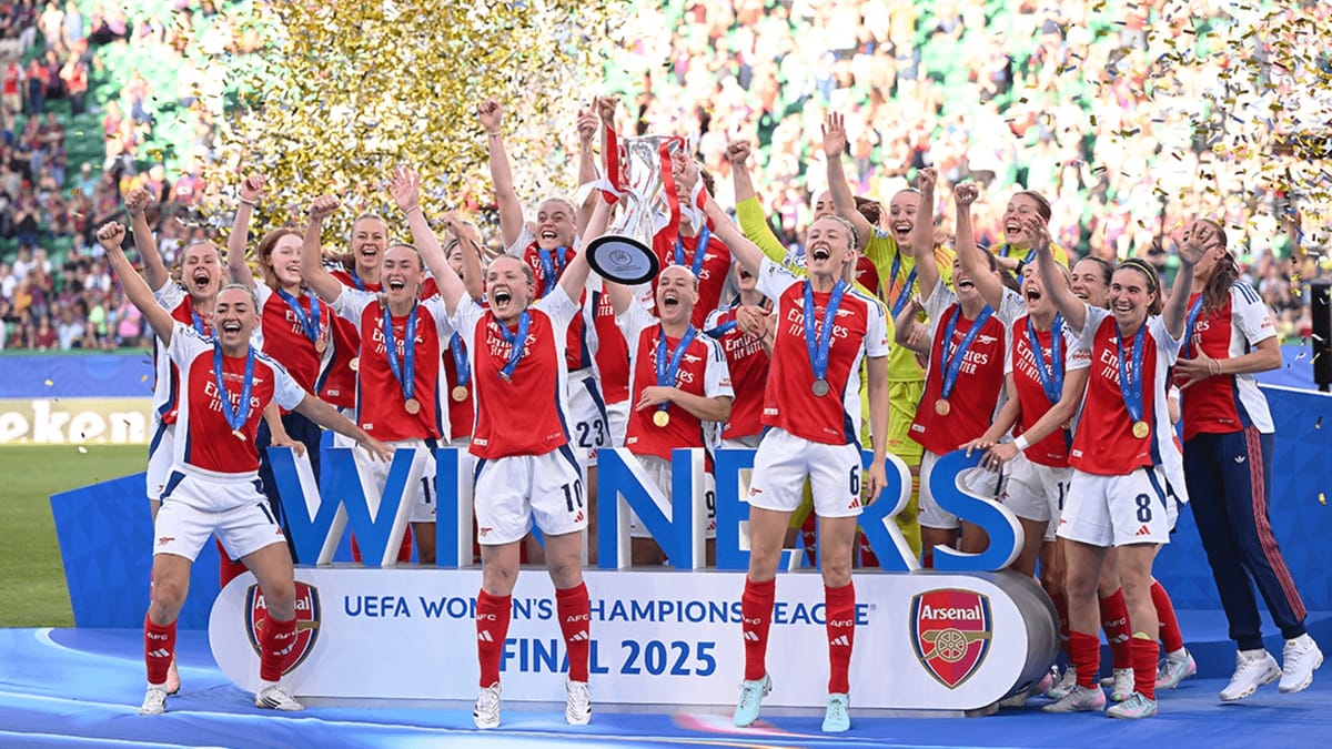 a group of celebrating women on a platform with a trophy, wearing Arsenal's red and white kits